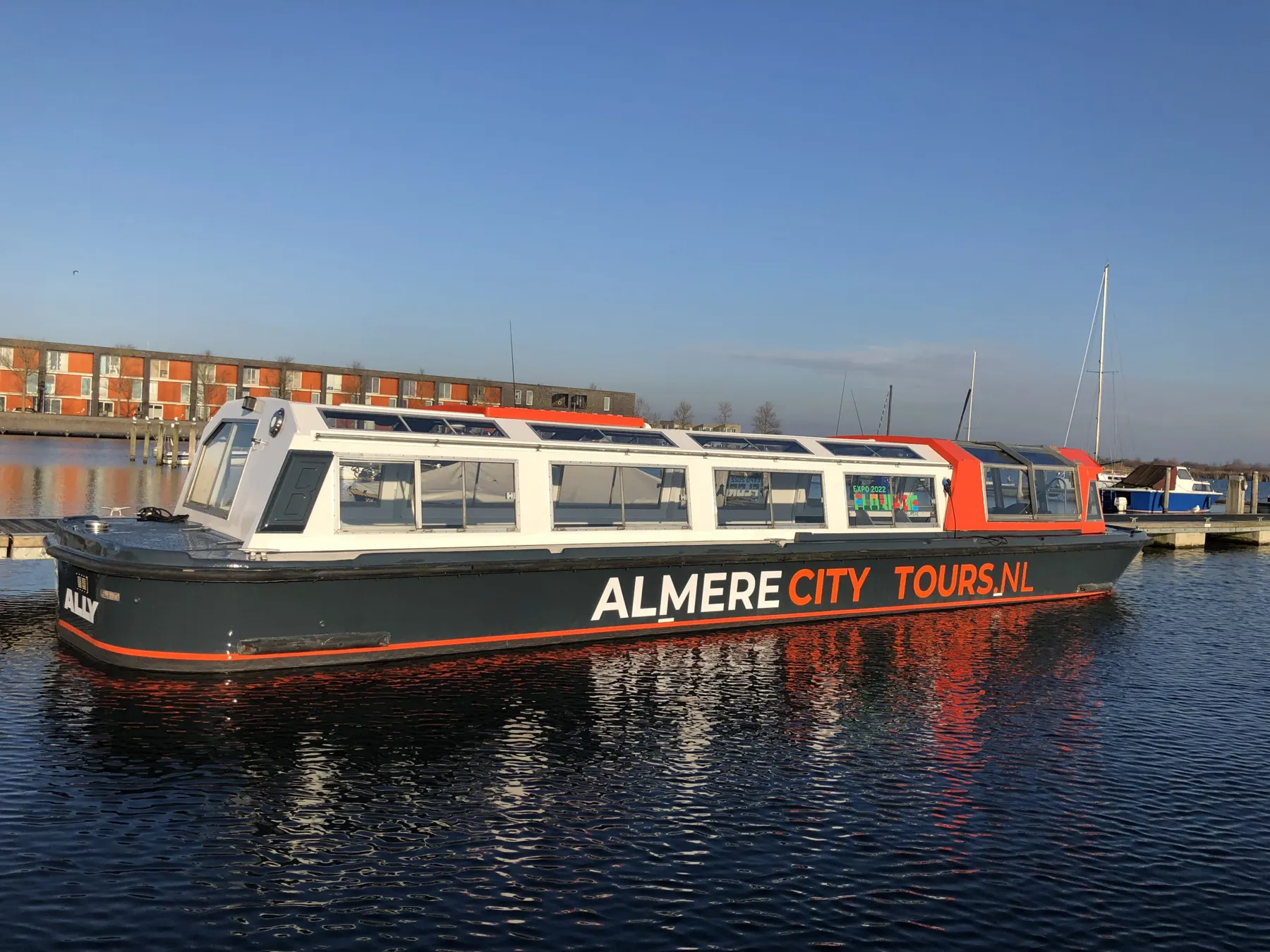 Boot van Almere City Tours op het water bij zonsondergang