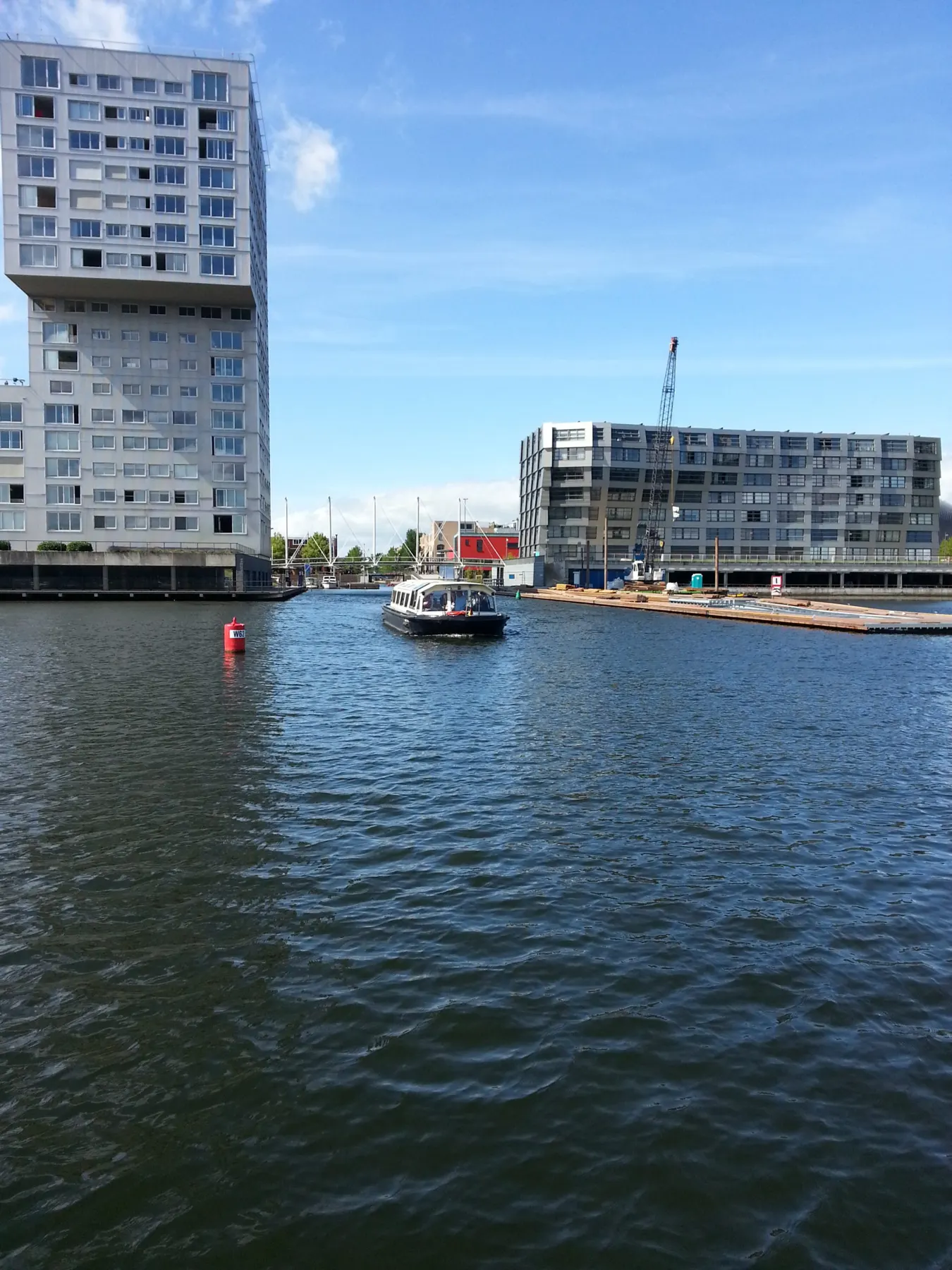Een boot in de haven van Almere met appartementen op de achtergrond